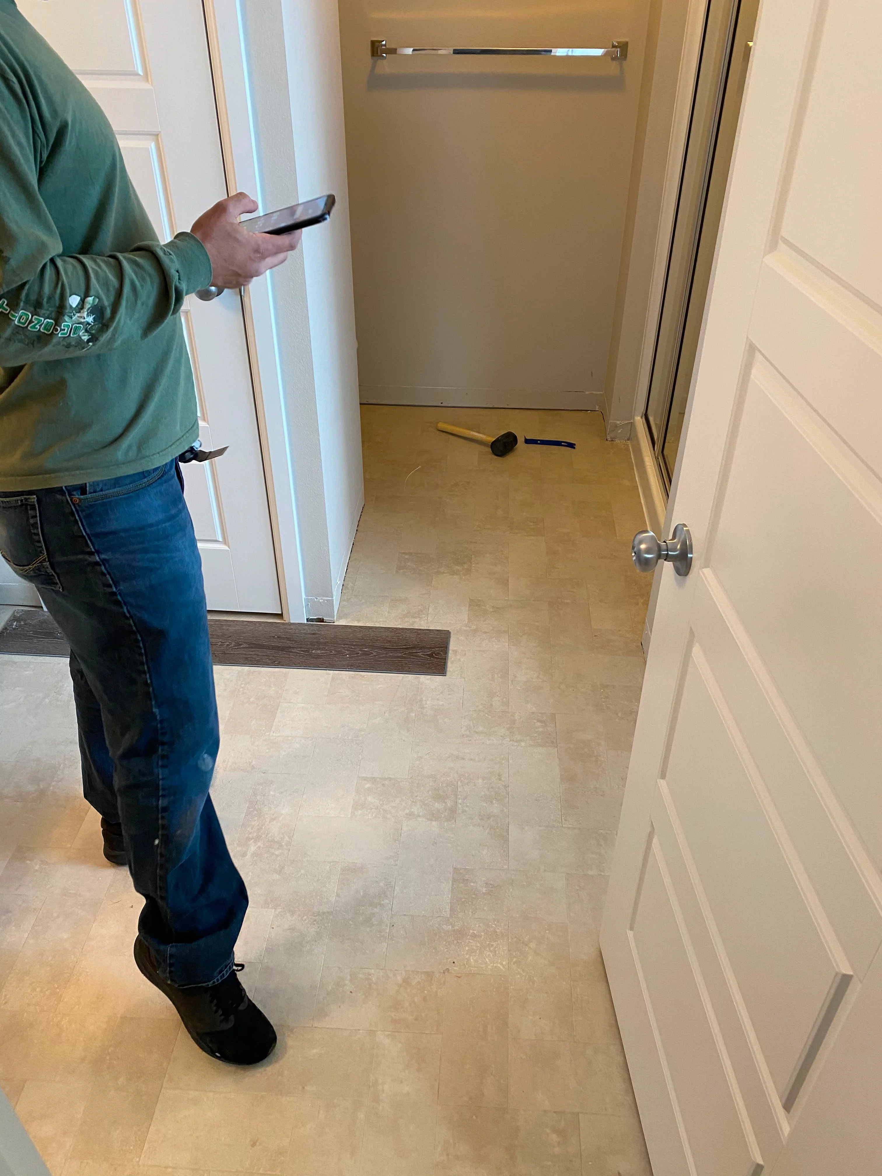 Luxury vinyl plank flooring installation in bathroom with wood transition trim