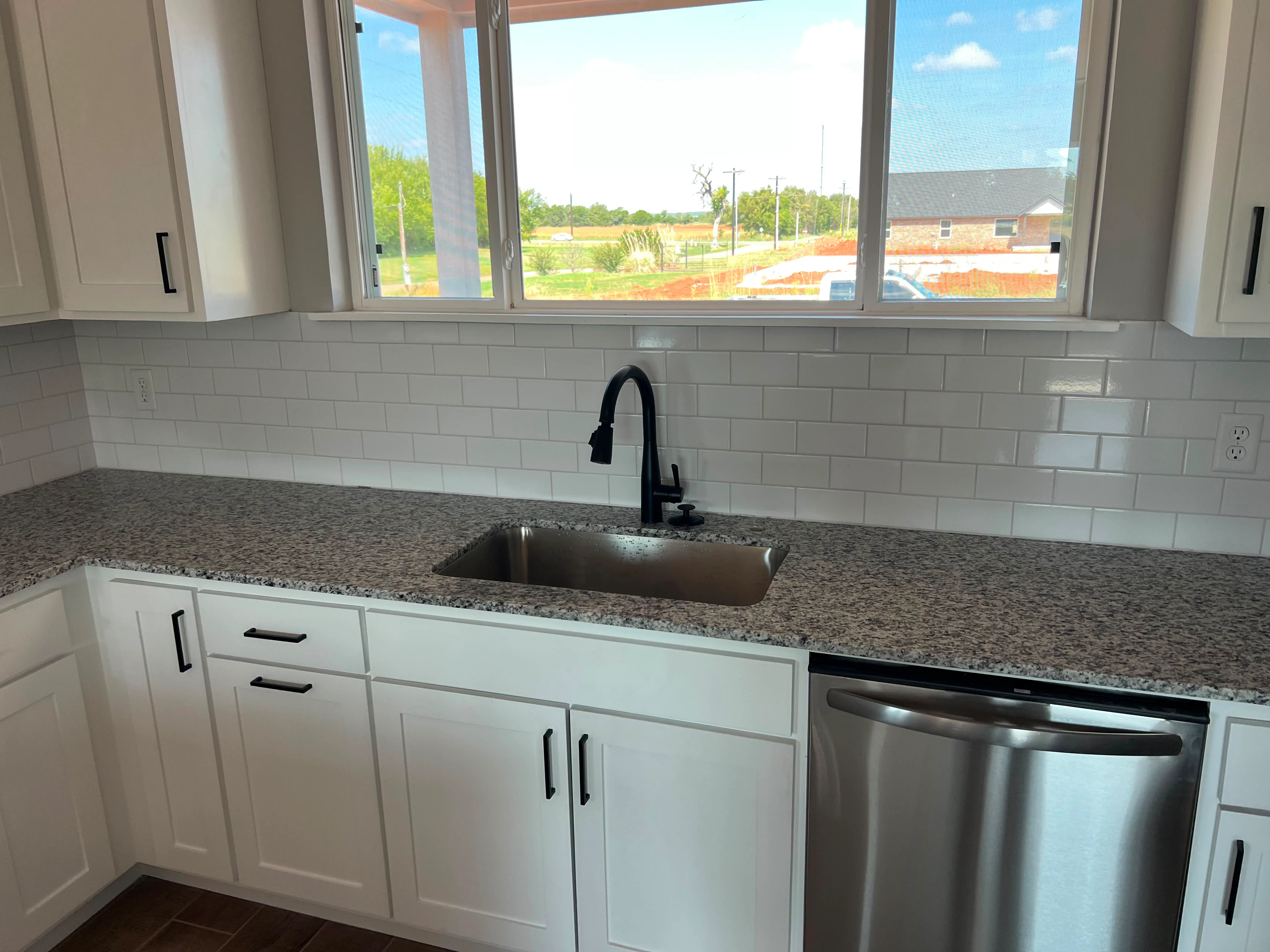 Modern kitchen with white cabinets, granite counters, subway tile backsplash, and stainless steel appliances