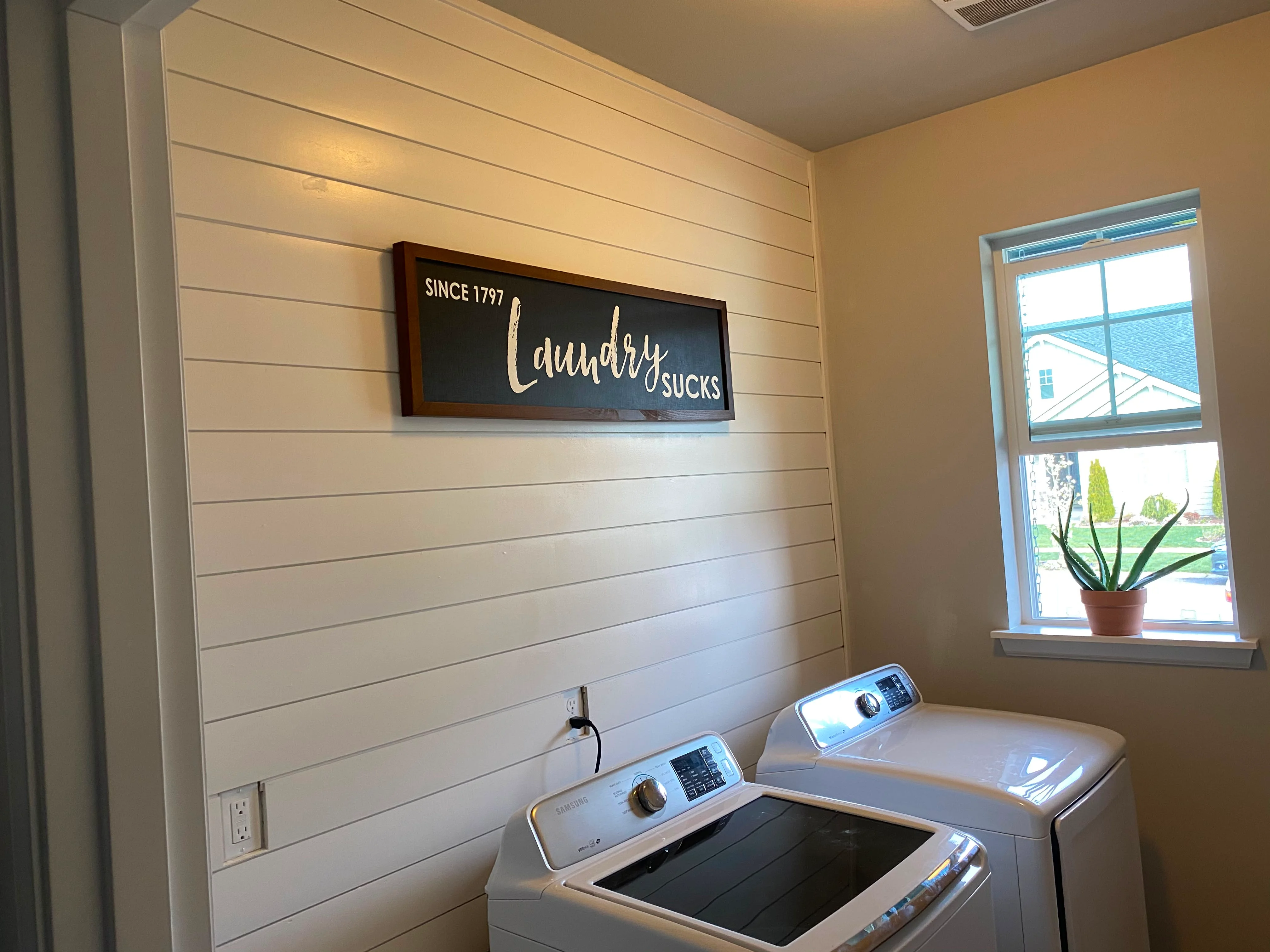Laundry room with white shiplap accent wall, recessed lighting, and modern appliances