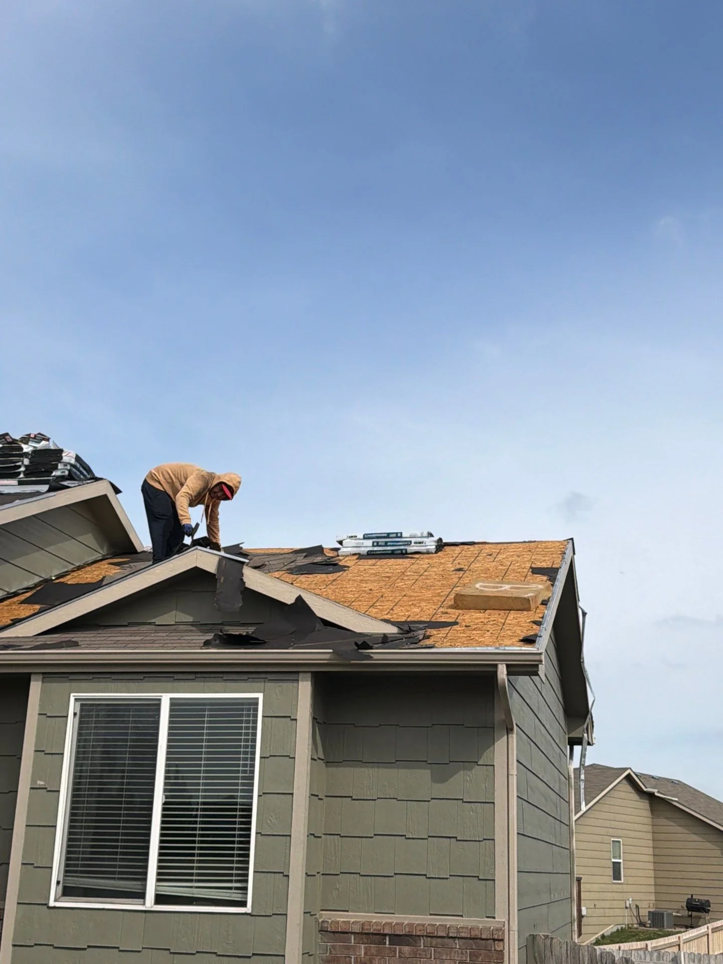 Roofer installing new architectural shingles on residential home roof in Moore, OK