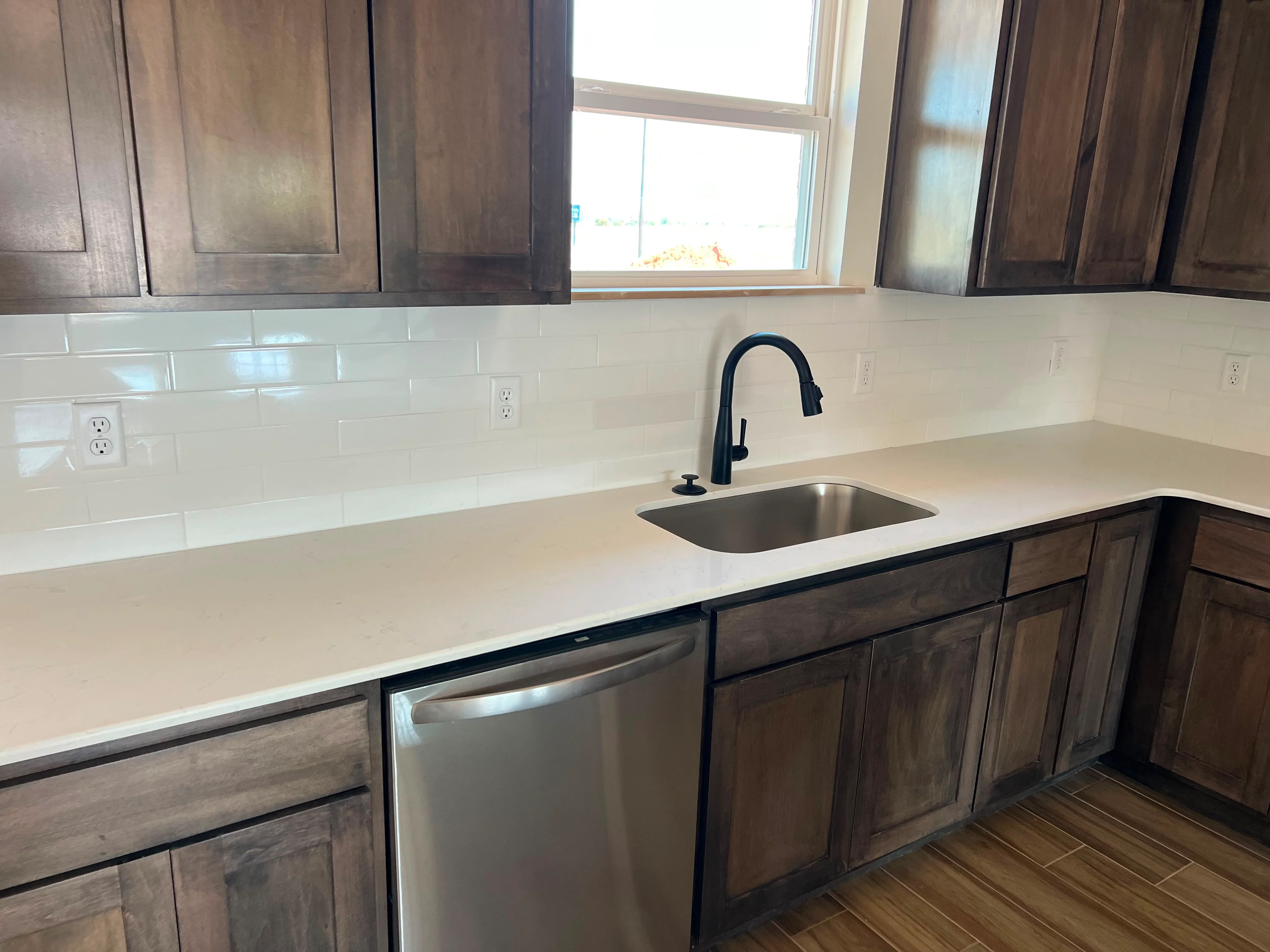 Kitchen with dark wood cabinets, white quartz counters, subway tile backsplash, and stainless steel sink